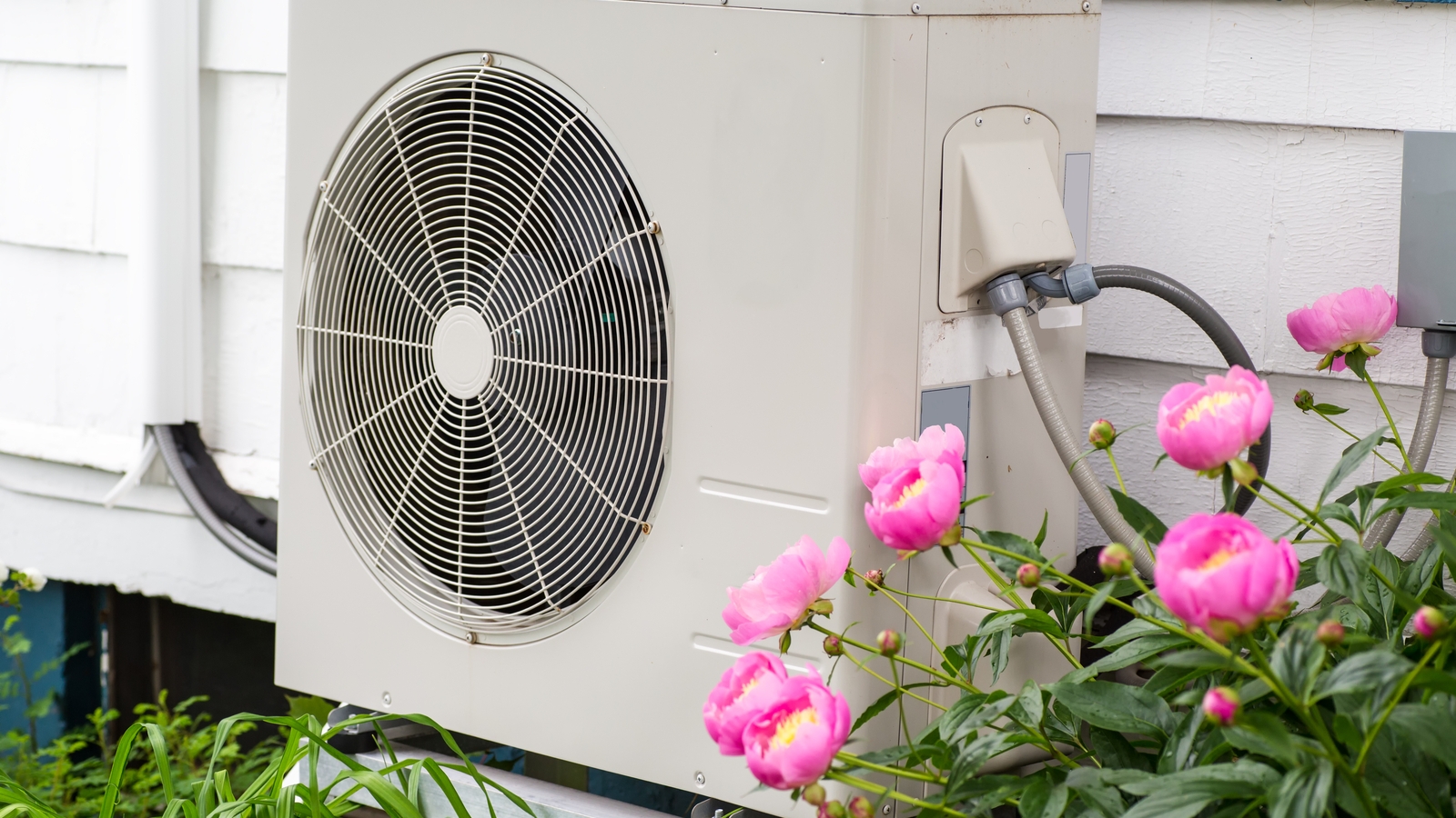 Heat Pump On Side of House Exterior Next to Pink Flowers